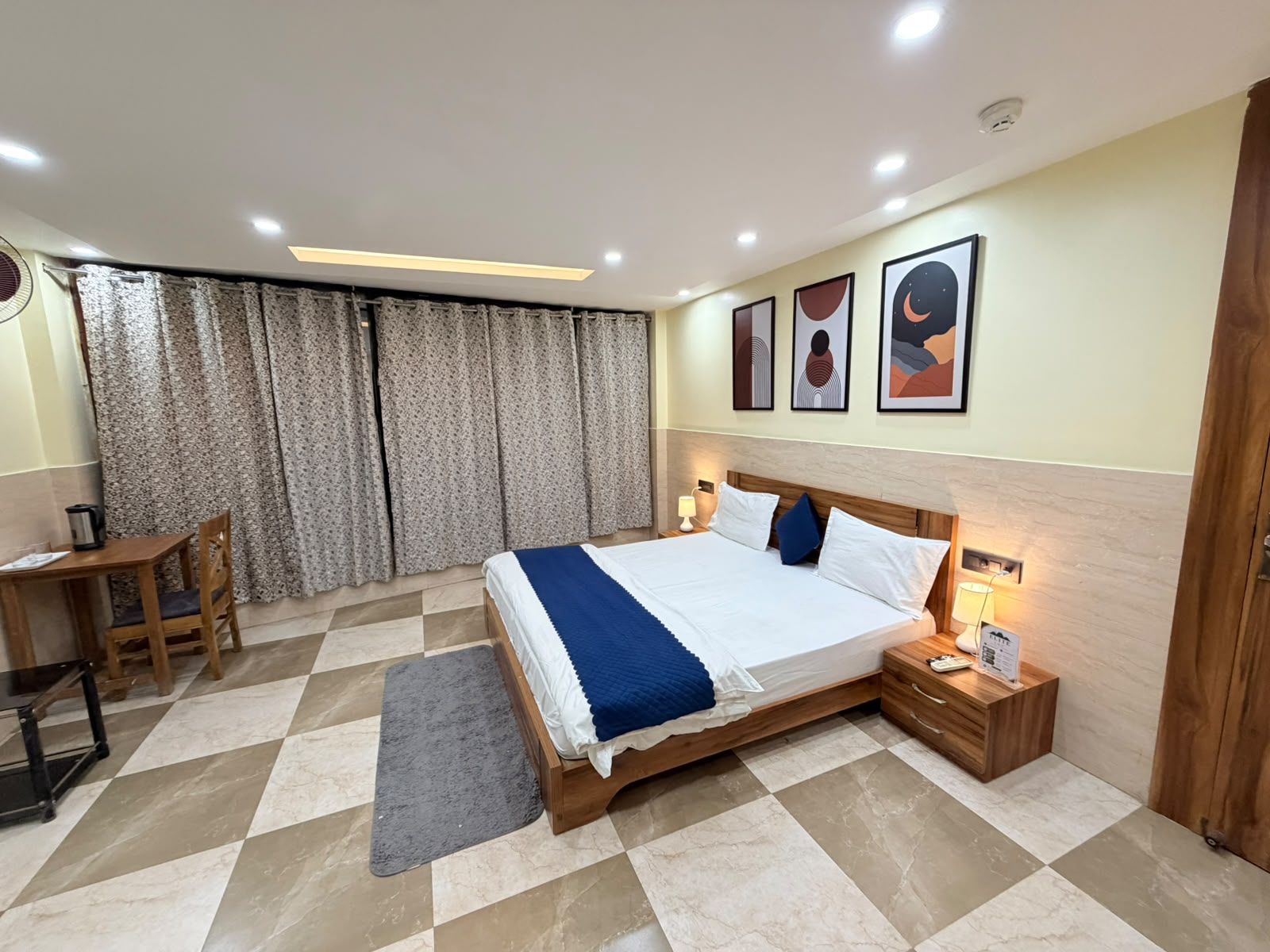 A hotel room with a large bed, a desk, a chair, and a window with curtains.