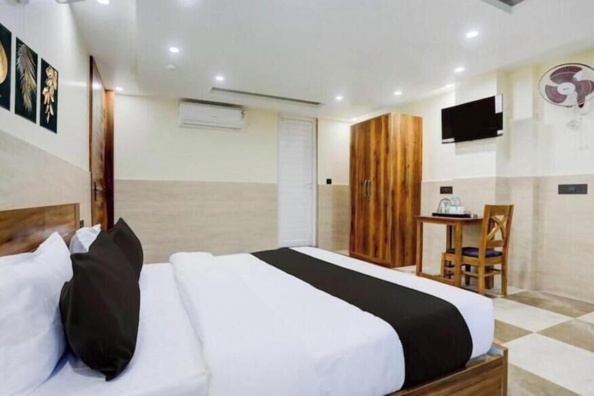 Ein Hotelzimmer mit Bett, Schreibtisch, Stuhl, Fernseher und Wandventilator.