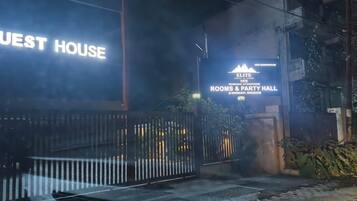 Un edificio con un letrero que dice 'GUEST HOUSE' y otro letrero que indica 'ELITE INN', mostrando habitaciones y un salón de fiestas.