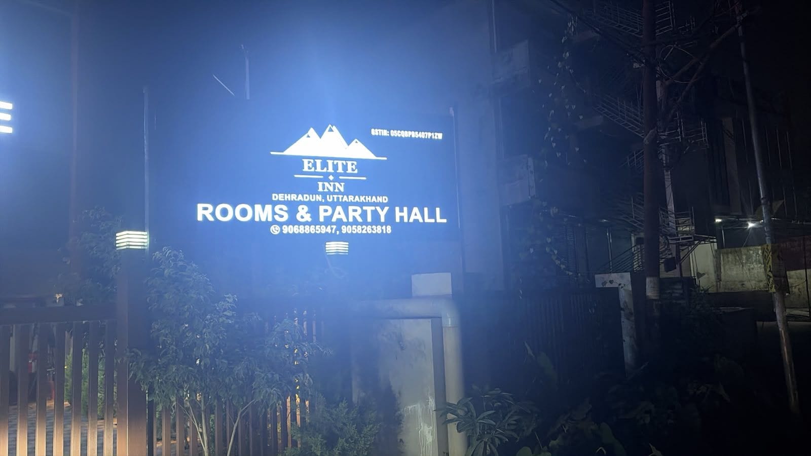 A sign for Elite Inn Dehradun, Uttarakhand, Rooms & Party Hall with contact numbers.