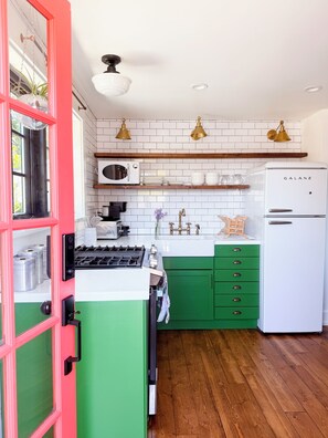 A kitchen with a gas stove, white refrigerator, and green cabinets. - Suite in the Foothills of LA for Extended Stays (La Crescenta-Montrose)