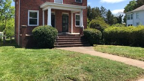 A two-story brick house with a front porch, steps leading to the door, and a well-maintained lawn. - 2-bedroom building in cool Richmond with refreshing AC (Richmond)