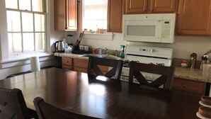 A kitchen with wooden cabinets, a white microwave, a stove, and a dining table with chairs. - 2-bedroom building in cool Richmond with refreshing AC (Richmond)
