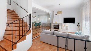 A modern living room with a staircase, a sofa, a fireplace, and a TV mounted on the wall. - Villa 'Modern  in Olhao' with Mountain View, Wi-Fi and Air Conditioning (Quelfes)