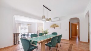 A dining area with a wooden table, green chairs, and pendant lights. - Villa 'Modern  in Olhao' with Mountain View, Wi-Fi and Air Conditioning (Quelfes)