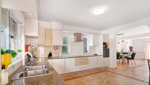 A modern kitchen with a granite countertop, stainless steel sink, and white cabinetry. - Villa 'Modern  in Olhao' with Mountain View, Wi-Fi and Air Conditioning (Quelfes)