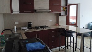 Una cocina con estufa, lavaplatos y taburetes de bar.