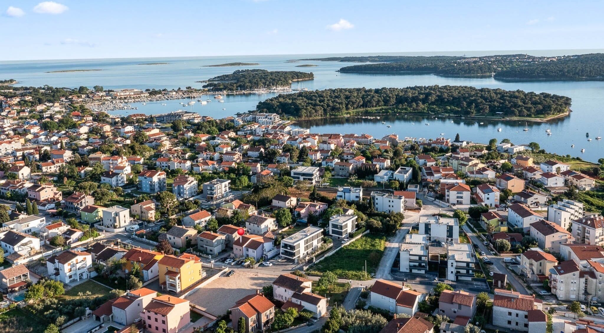 An aerial view of a coastal town with residential buildings, marina, and surrounding water bodies.