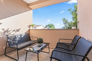 Ein Balkon mit zwei schwarzen Stühlen, einem kleinen Tisch und einem Blumentopf.