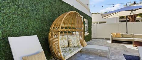 A patio with a white lounge chair, a wicker sofa, and a white couch.