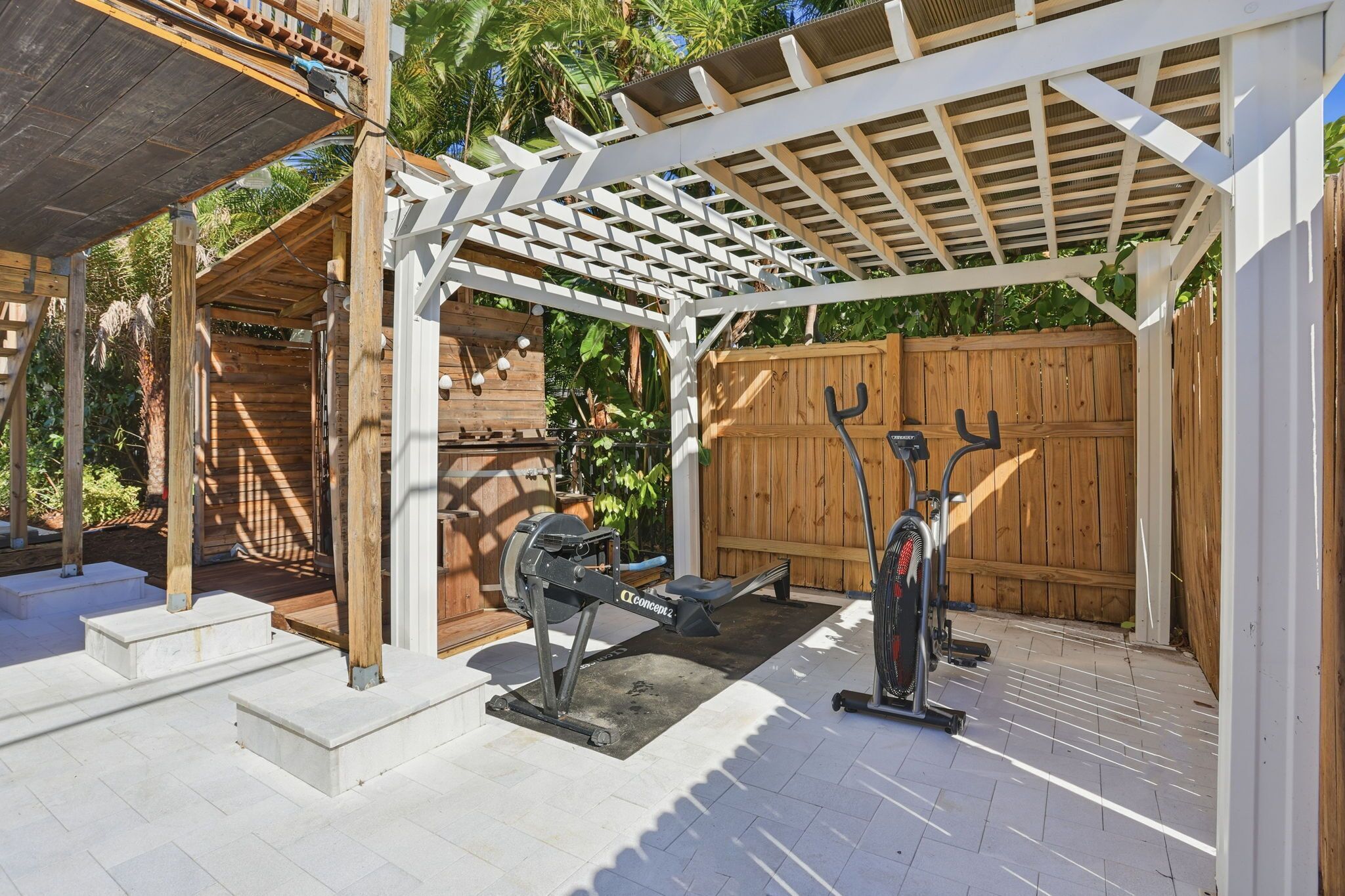A covered outdoor area with a stationary exercise bike and a treadmill.