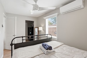 A bedroom with a bed, a ceiling fan, an air conditioning unit, a window with blinds, and a door leading to a closet. - Tropical Pool Oasis Near Atlantic Ave & Beach (Delray Beach)