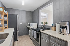 A modern kitchen with a refrigerator, microwave, stove, and coffee maker. - Tropical Pool Oasis Near Atlantic Ave & Beach (Delray Beach)