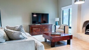 Una sala de estar con sofá, mesa de centro, televisor, chimenea y un aparador.