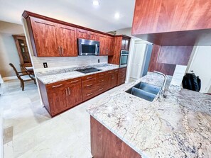 A kitchen with wooden cabinets, a stainless steel microwave, and a built-in oven. - Luxurious Oasis - Heated Salt Pool - Pool Table - 4BR Near Miami (Cutler Bay)