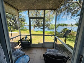 Eine überdachte Terrasse mit Seeblick, einem Tisch mit Stühlen und einer Satellitenschüssel.