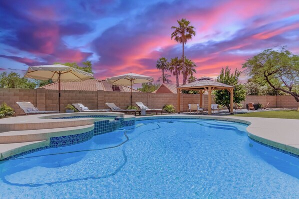 A swimming pool with lounge chairs and umbrellas, surrounded by a brick wall and palm trees. - Scottsdale 4 Bdrm Retreat, Pool, Spa, Prime Location! (Scottsdale)