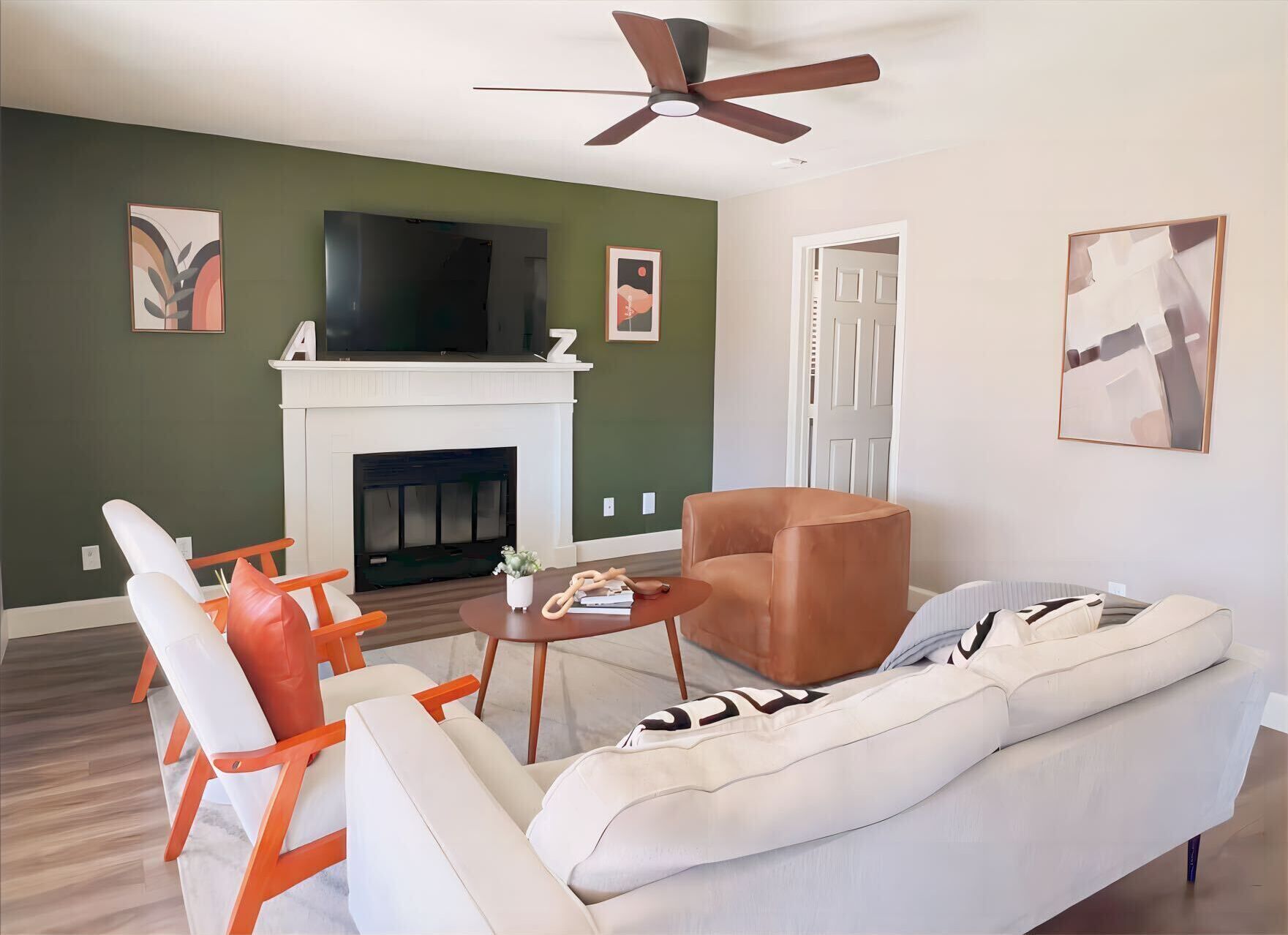 A living room with a fireplace, a television, a ceiling fan, and a sofa.