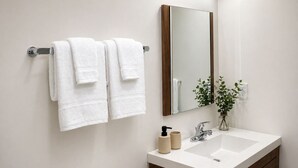 Een badkamer met een witte wastafel, een spiegel en twee handdoeken aan een handdoekhouder.