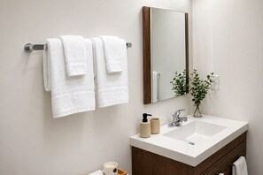 Ein Badezimmer mit einem weißen Waschbecken, einem Spiegel und zwei Handtüchern, die an einem Handtuchhalter hängen.