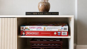 Een plank met een Monopoly spelbord, een boek getiteld 'New York Deco' en een decoratieve vaas.