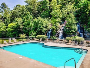 Ein Swimmingpool mit Liegestühlen und einem Wasserfall.