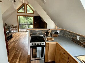 A kitchen with a stone backsplash, wooden cabinets, a built-in oven, and a large window overlooking greenery.