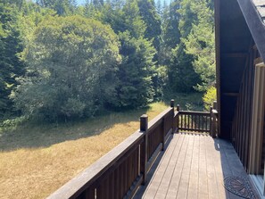 A wooden deck with a railing overlooking a forested area.