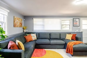 Una sala de estar con un sofá modular, un tapete colorido y una pared con una cita inspiradora.