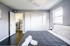 Une chambre Ă coucher comprenant un lit, une armoire, une fenĂȘtre et une porte donnant sur une autre piĂšce.