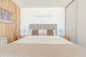 Ein modernes Schlafzimmer mit einem großen Bett, Holzwandverkleidungen und einem gerahmten Bild.