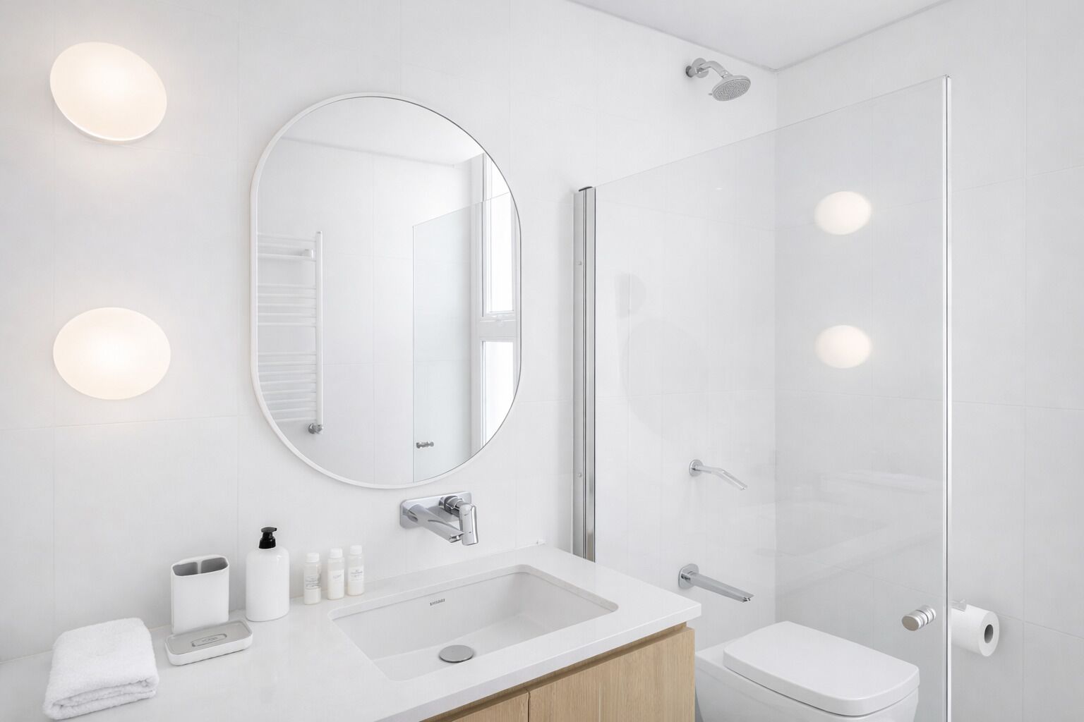 A modern bathroom with a large mirror, a sink, a toilet, and a shower.