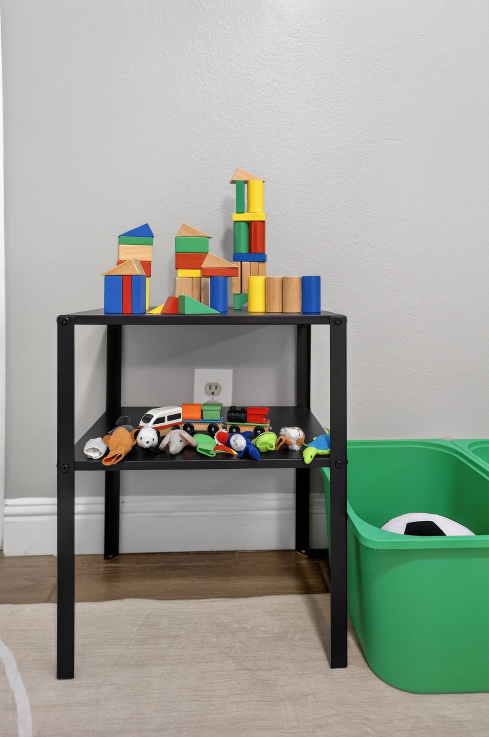 A black metal shelf unit with colorful building blocks on top and various toys on the lower shelf.