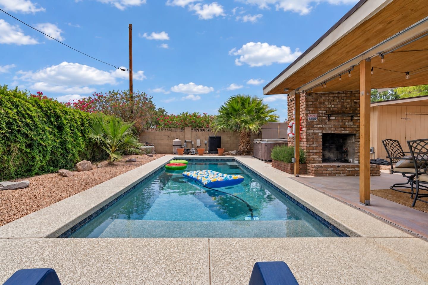 A swimming pool with a brick fire pit and outdoor furniture.