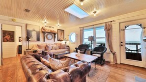 Ein gemütliches Wohnzimmer mit einer Ledersofa, einem Holztisch und Meerblick durch große Fenster.