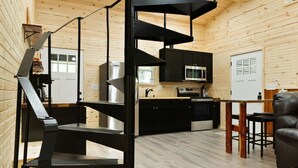 Un interior moderno con una escalera de caracol, paredes de madera, una cocina y un comedor.