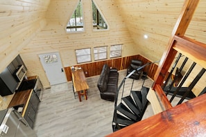 Un intérieur en bois comprenant un coin repas, un canapé et un escalier.