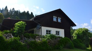 A two-story house with a sloped roof, white windows, and a satellite dish. - Eden Apartment (Glödnitz)