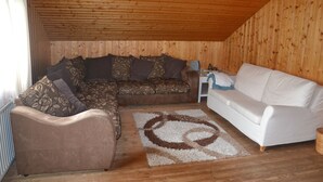 A wooden-paneled room with a brown sofa, a white sofa, and a patterned rug. - Eden Apartment (Glödnitz)