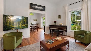 A living room with a piano, a television, and a dining area with a table and chairs.