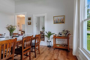 Spiseplads med træstole, et bord dækket til to og en vinvogn med glas.