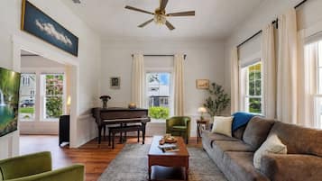 Una sala de estar con un piano, un sofá, una mesa de centro y un televisor.