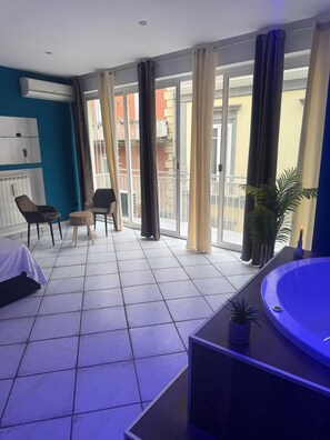 Ein modernes Wohnzimmer mit großem Fenster, einer Couch, einem Couchtisch und einem kleinen Billardtisch.