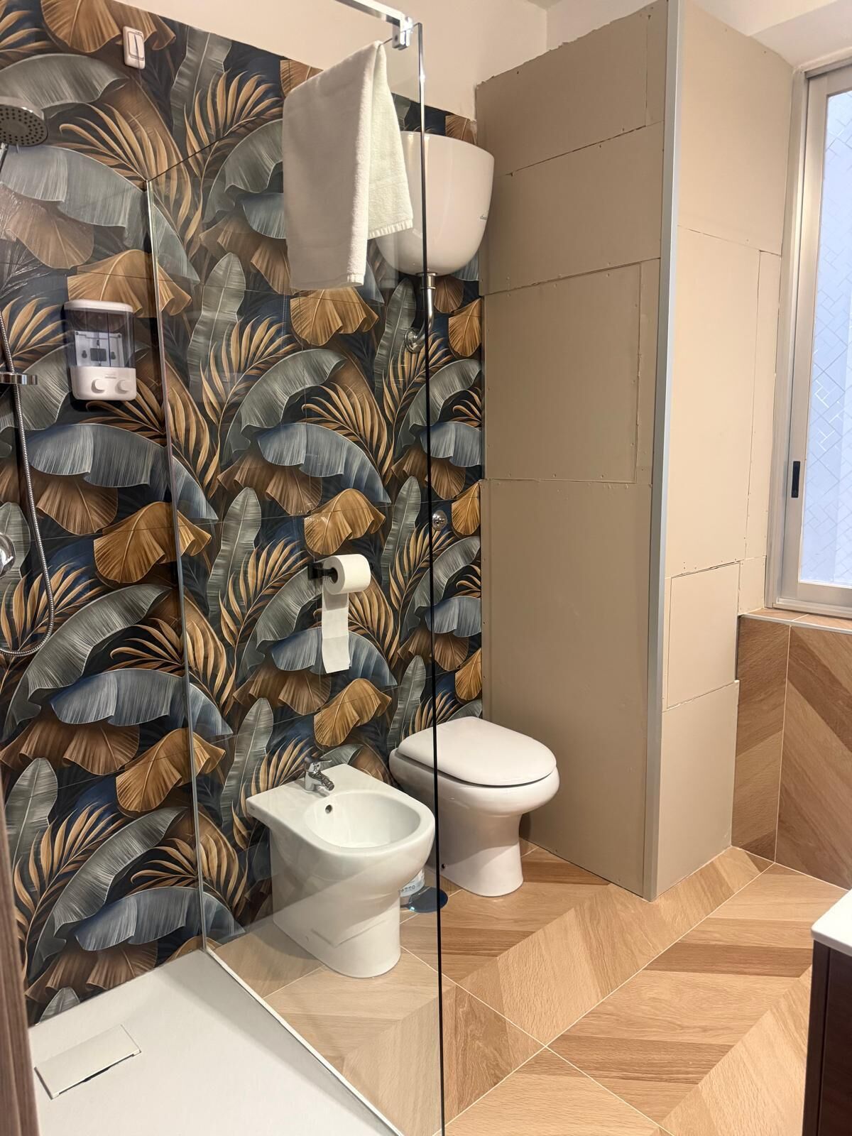 A bathroom with a shower, toilet, bidet, and a mirror.