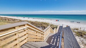 Une promenade en bois menant à une plage, avec un ciel dégagé.