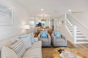 Ein modernes Wohnzimmer mit einer Couch, Sesseln, einem Couchtisch und einer Treppe.