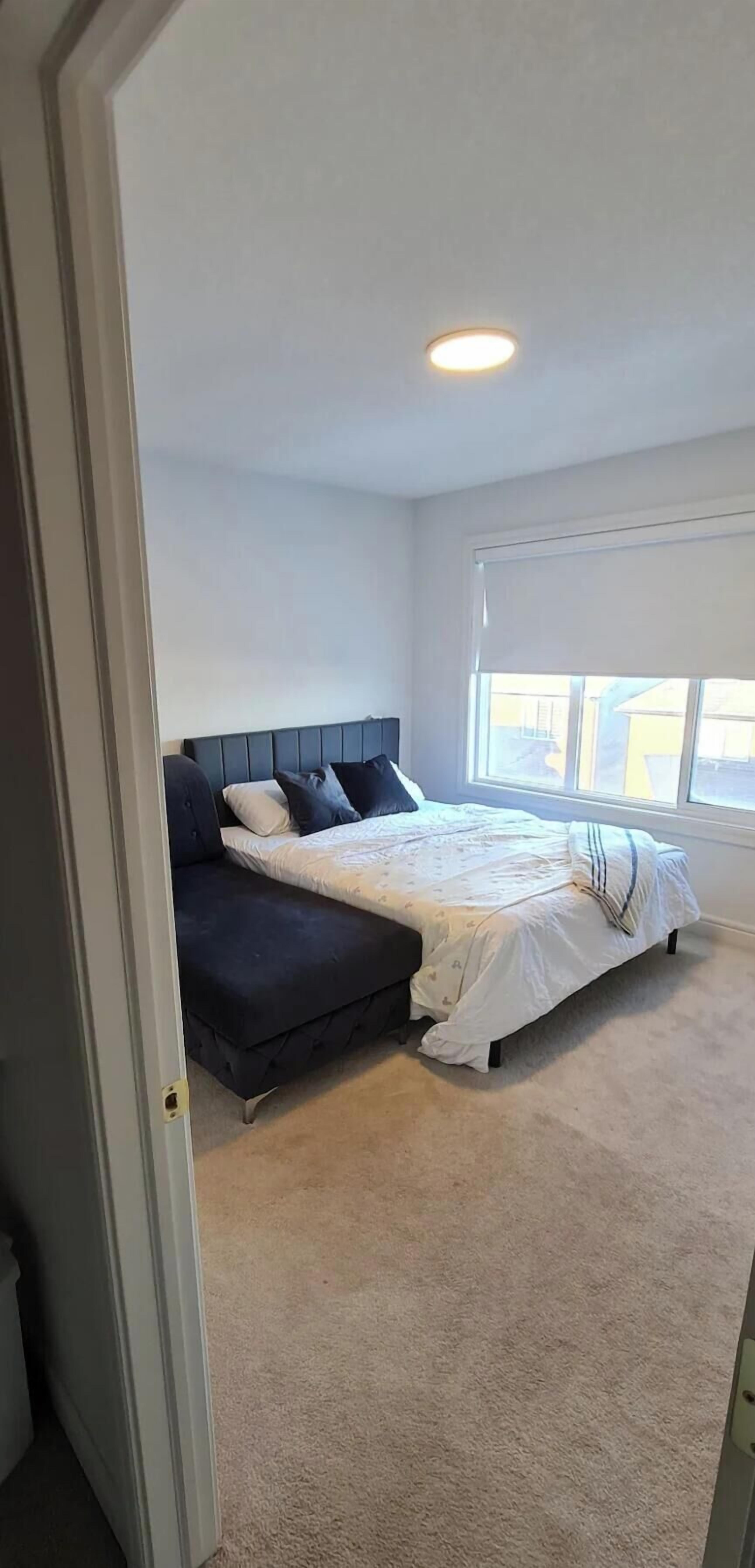 Un dormitorio con cama, sofá, ventana y puerta.