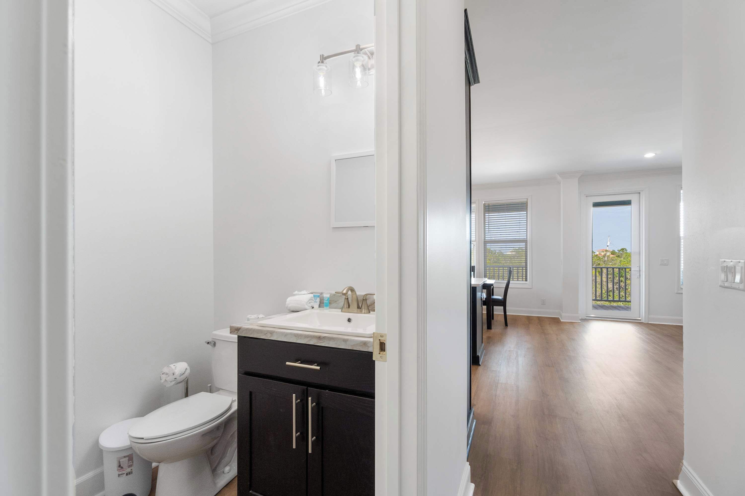 A bathroom with a toilet, sink, and dark cabinets.