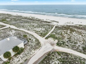 Vue aérienne d’une zone côtière comprenant une plage, une route et un bâtiment doté d’un toit en pente.