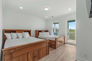 Une chambre avec deux lits en bois, un balcon avec vue et une grande fenêtre.